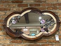 Front view of mirror showing oval carved wood frame and stained glass floral design