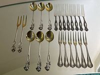 All 22 pieces arranged on mirrored surface showing forks and spoons