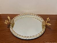 Front angled view of the vintage vanity tray showing the mirrored surface, clear lucite faceted trim, and gold fish handles.