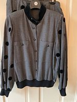 Grey women's jacket with large black velvet polka dots on sleeves, button front, ribbed black collar and cuffs