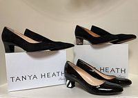 Three pairs of pumps arranged on branded Tanya Heath shoe boxes: black suede with plain heels, black suede with glitter heels, and black patent leather with striped heels