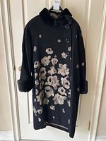Full front view of black wool coat with beige jacquard floral pattern and mink trim