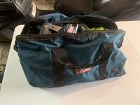 Blue Ryobi tool bag filled with various Ryobi tools including drills and saws