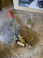 Full view of hand winch showing red handle, steel cable coiled with metal hooks, and background cardboard box.