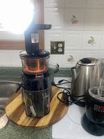 Photo showing Salton Vita Pro juicer and General Electric electric kettle on countertop, black & orange juicer with clear parts, stainless steel kettle.