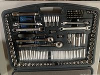Open case showing interior tools laid out in molded slots, various socket sizes, wrenches, bits visible