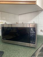 Front view of the Panasonic inverter microwave showing the door, brand logo, and control panel with digital keypad and display.