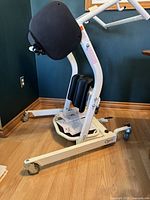 Side angle of Pro Mover 500 Stand Assist showing padded knee and back supports, caster wheels, and white metal frame.