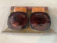 Front view of the trailer light kit in packaging showing two red tail lights and two amber side marker lights.