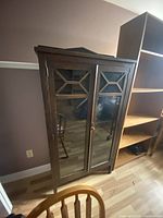 Front view of the vintage wooden cabinet with glass doors showing geometric wooden trim details and overall height.