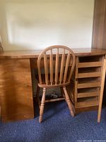 Front view of the solid wood desk with matching chair positioned in front, showing left cabinet and right shelves.