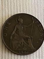 Reverse side of 1907 Great Britain one penny coin showing Britannia seated with trident and shield, date and denomination.