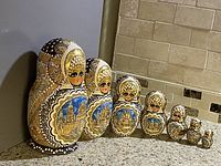 Photo showing the full set of 7 Russian nesting dolls lined up in descending size order, highlighting the detailed hand painted decoration and traditional motifs.