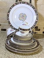 Stacked view of dinner plates, bread and butter plates, dessert plates, soup bowls, cups and saucers displaying Runnymede Brown Wedgwood design pattern