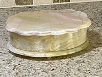 Closed shell-shaped alabaster jewelry box showing polished exterior with natural stone veining.