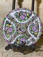 Full view of vintage Chinese Famille Rose porcelain plate on a stand, showing floral and bird motifs with purple and green border.