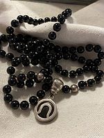 Full view of the black onyx bead necklace featuring silver beads and the large round silver pendant with black inlay.