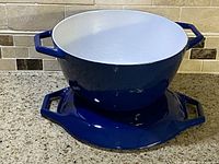Side angle of vintage navy blue Copco Danish cast iron Dutch oven on granite countertop showing pot and separate base/trivet