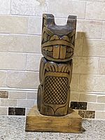 Front view highlighting facial features and textured torso carving.