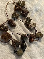 Full view of the jade animal charm necklace on cloth showing multiple carved charms and beads.