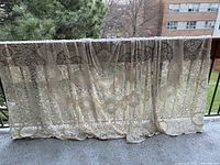 Full view of the large lace tablecloth draped over a balcony railing, showing the intricate lace design and size.
