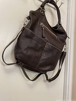 Front and side view of chocolate brown Roots vintage leather tote bag with crossbody strap and handles.