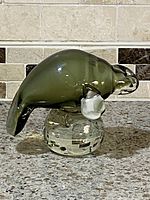 Side front view of Murano glass manatee paperweight showing the green manatee on clear base