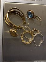 Angle showing white metal hinged hoop alongside gold earrings