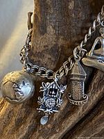 Close-up view showing globe, cuckoo clock, and Luzern tower charms on sterling silver chain bracelet.