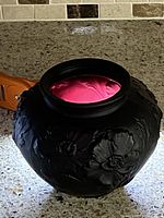 Photo showing black amethyst satin glass vase with embossed poppy floral design from a side angle, highlighting the matte finish and floral relief.