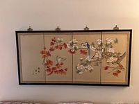 Full view of the four panel Oriental wall screen hung on a wall showing the birds and floral artwork.