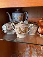 Photo of the Japanese tea set showing teapot, sugar bowl, creamer, cups stacked on saucers with visible gold dragon designs