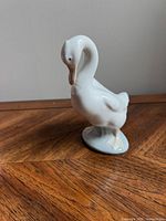 Front view of the white porcelain goose figurine showing detailed sculpting of head and wings, standing on an oval base.
