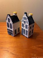 Pair of Blue Delft porcelain miniature houses with distinct Dutch facades on wooden surface.