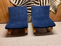 Front view of two royal blue upholstered chairs side by side against a wood-paneled wall.
