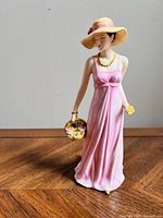 Front view of Royal Doulton figurine showing woman in pink dress with hat and flower basket