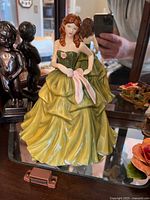 Front view of Royal Doulton figurine depicting a woman in a yellow dress with green bodice and pink scarf.