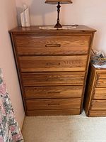 Front view of the vintage wooden dresser showing all five drawers and wood grain finish