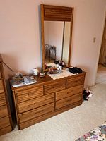 Front view of vintage 7 drawer wood dresser with matching framed mirror mounted on top, items on dresser surface not included.