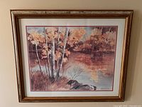 Framed watercolour painting showing birch trees by a lake with autumn colors, signed Joan Burr 1986.