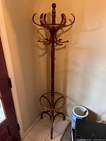 Full view of the vintage MCM bentwood Thonet style coat and hat rack positioned in a corner, showing the entire item and its condition.