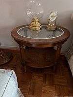 Oval vintage wooden side table with glass inset top and cane bottom shelf, showing wood finish and turned legs with minor aging marks