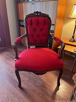 Front view of vintage Baroque style armchair with red velvet tufted backrest and seat, visible wood carvings and cabriole legs.
