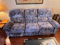 Front view of vintage three-seat sofa showing the upholstery, cushion texture, and manual recliner on the left seat.