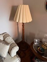 Full view of vintage floor lamp next to upholstered couch and wooden side table with decor items