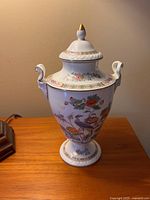Front view of the Wedgwood Kutani Crane covered urn showing detailed colorful crane and floral design, finial lid, and side scroll handles.