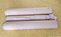 Three rolls of vintage wallpaper lying side by side, showing size and condition of paper wrapping.