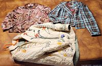 Three jackets laid out on a surface showing the velvet paisley, plaid, and embroidered floral designs.