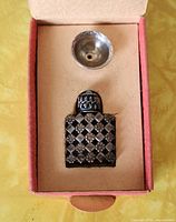 Photo of perfume bottle and small metal funnel in original cushioned box with red trim