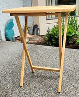 Side view of the folding wood table showing the legs and the thin profile of the tabletop.